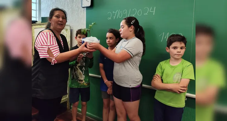 A turma realizou a entrega de mudas de árvores, simbolizando o compromisso com o cuidado com a natureza.