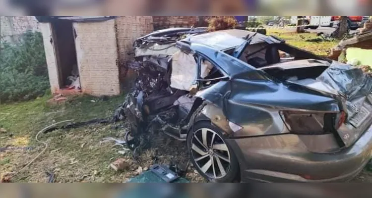 O carro ficou totalmente destruído após bater violentamente contra uma árvore e contra o muro de uma residência