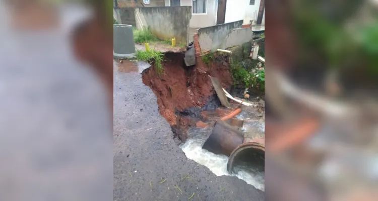 Excesso de água faz asfalto ceder e derruba parte de muro de casa