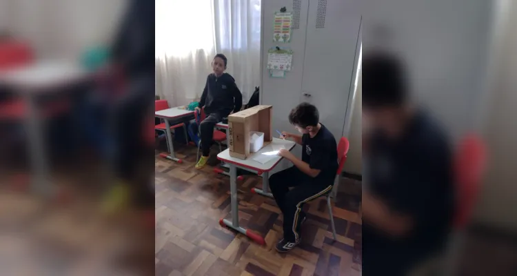 Entusiasmados com a proposta, a turma organizou a sala com a representação de uma urna, alunos na função de mesários e cadernos de votação.