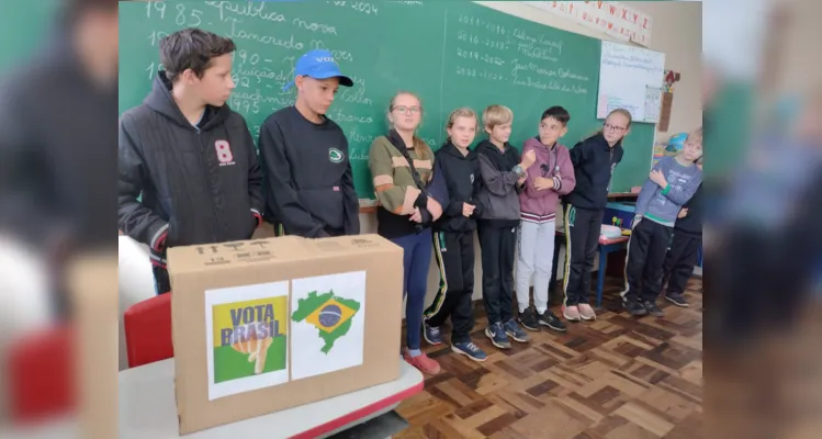 Entusiasmados com a proposta, a turma organizou a sala com a representação de uma urna, alunos na função de mesários e cadernos de votação.