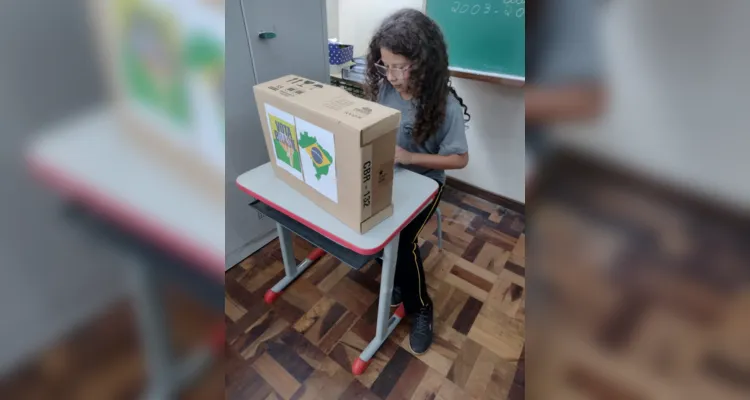 Entusiasmados com a proposta, a turma organizou a sala com a representação de uma urna, alunos na função de mesários e cadernos de votação.