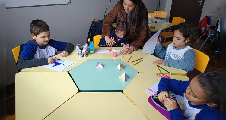 A turma utilizou modelos físicos, o livro didático e vídeos instrutivos para consolidar o aprendizado.