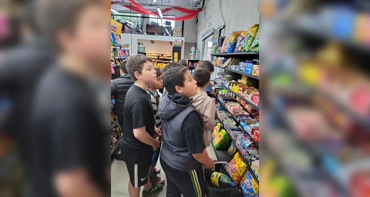 A proposta consistia em cada alunos levar um valor em dinheiro, algo simbólico, para a turma realizar compras coletivas e experienciar na prática os conceitos estudados.