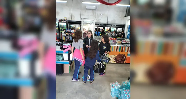A proposta consistia em cada alunos levar um valor em dinheiro, algo simbólico, para a turma realizar compras coletivas e experienciar na prática os conceitos estudados.
