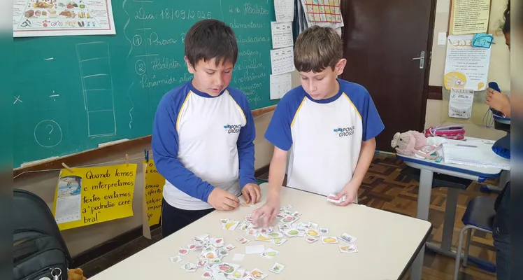 A classe usou variados recursos pedagógicos, como a videoaula do Vamos Ler e uma representação da pirâmide alimentar, e realizou trabalhos práticos sobre o tema.