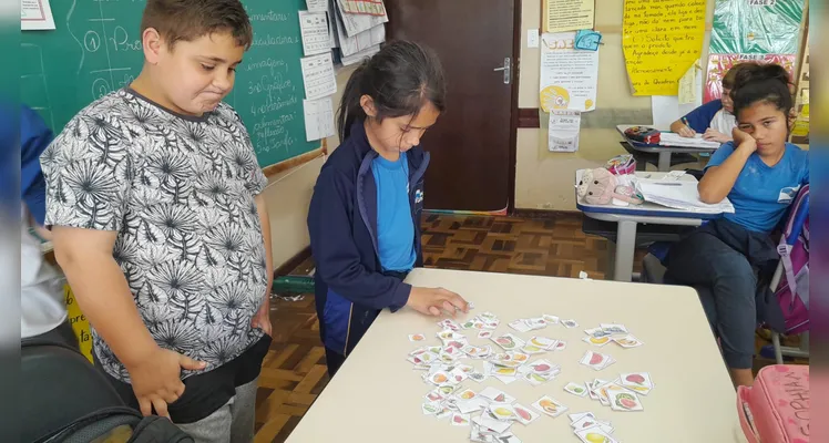 A classe usou variados recursos pedagógicos, como a videoaula do Vamos Ler e uma representação da pirâmide alimentar, e realizou trabalhos práticos sobre o tema.