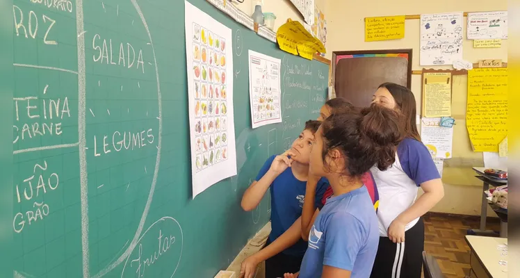 A classe usou variados recursos pedagógicos, como a videoaula do Vamos Ler e uma representação da pirâmide alimentar, e realizou trabalhos práticos sobre o tema.