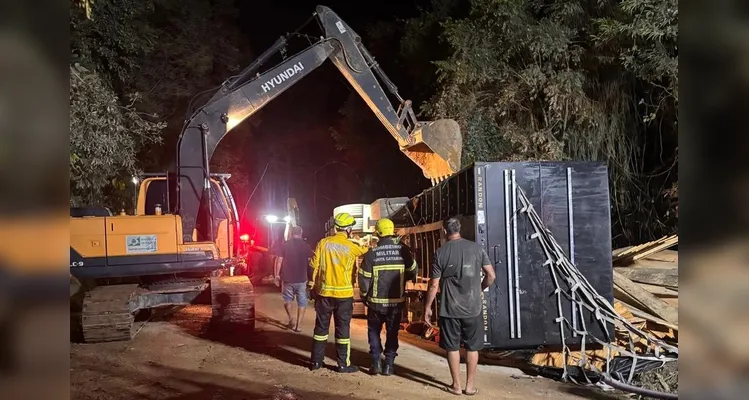 Carreta carregada com madeira tombada sobre carro
