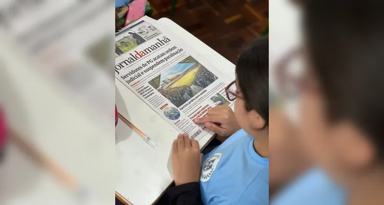 Os alunos tiveram contato com exemplares do Jornal da Manhã, explorando a organização do periódico, identificando diferentes seções e realizando atividades presentes na publicação.