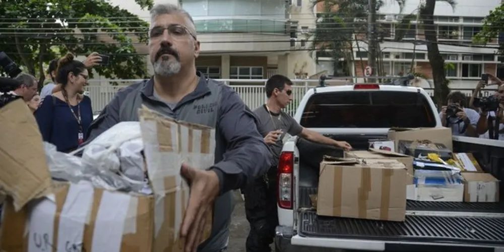 Policiais carregam caixas apreendidas em endereço ligado a suspeito de matar a vereadora Marielle Franco e o motorista Anderson Gomes 