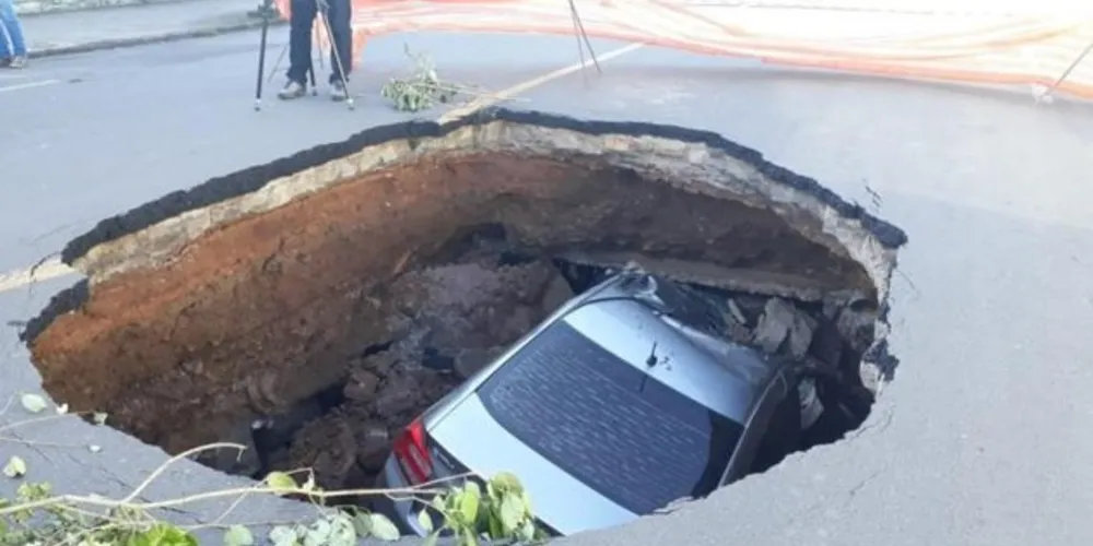 O carro, um Honda City, estava atrás de um caminhão carregado de terra quando foi engolido