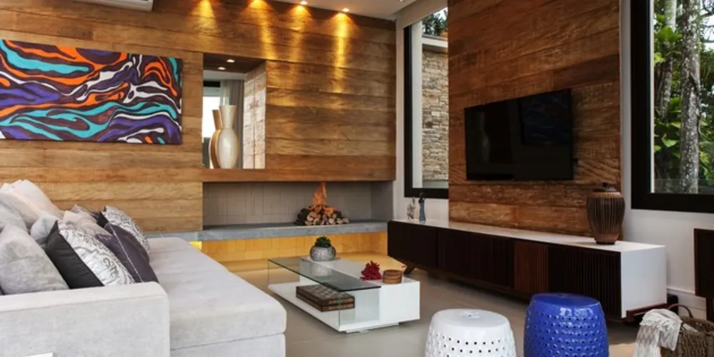 Madeira reveste as paredes. Mesa de 12 lugares e suíte se destacam na residência