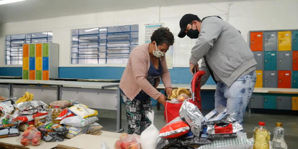Em um sistema de rodízio de professores, agentes I e II e também pedagogos e diretores, organizam os kits de merenda para distribuir às famílias