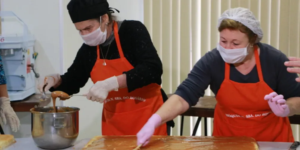 Três voluntárias trabalham na produção do bolo