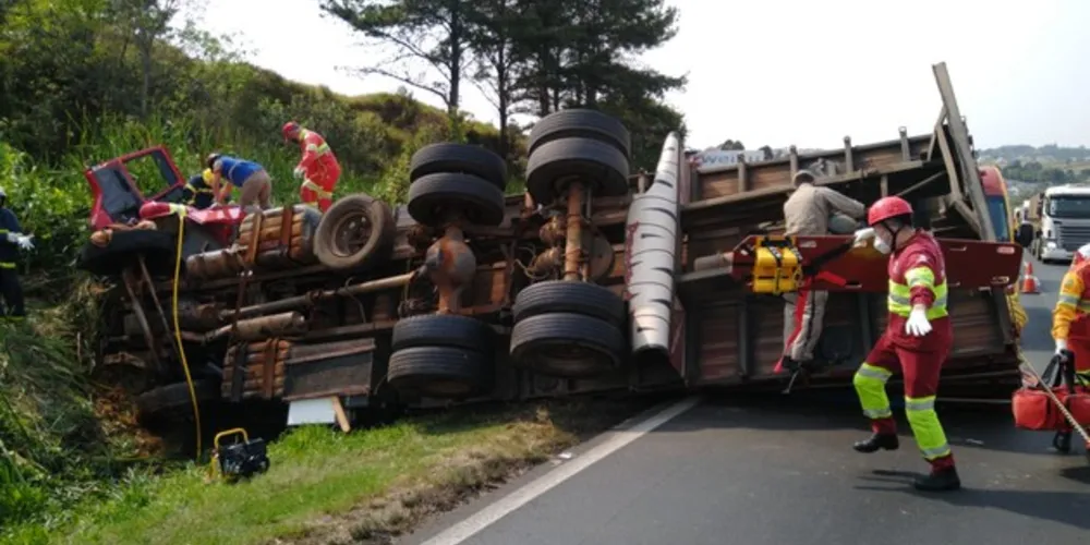 Vítimas ficaram enclausuradas na cabine do caminhão e socorristas fazem o resgate