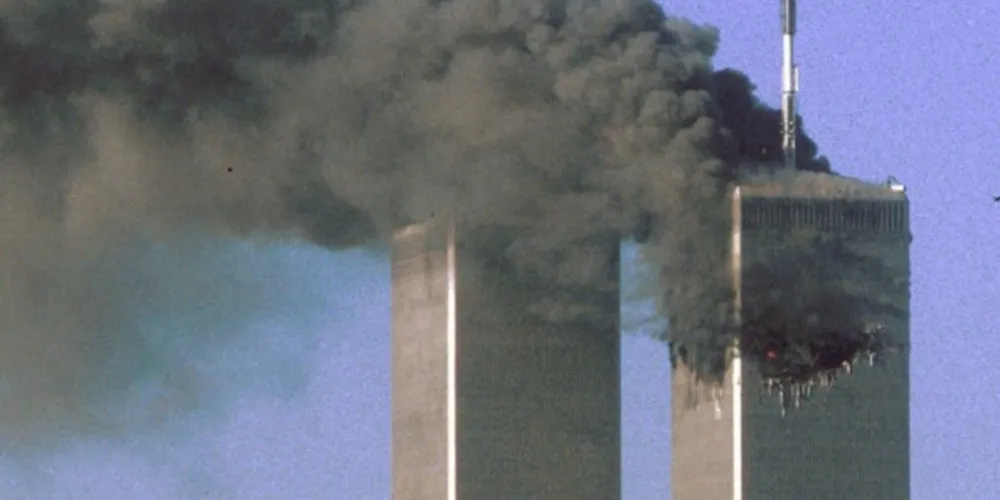 Segundos antes, avião do voo 175 da United Airlines é visto se aproximando da Torre Sul do WTC, em Nova York, enquanto a Torre Norte pega fogo, durante os ataques terroristas do 11 de Setembro