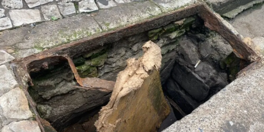 Ao invés de tampa, uma placa de madeira foi colocada pelos lojistas para evitar acidentes.