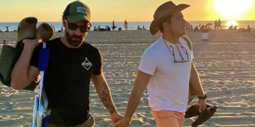 Marco Calvani e Marco Pigossi de mãos dadas na praia