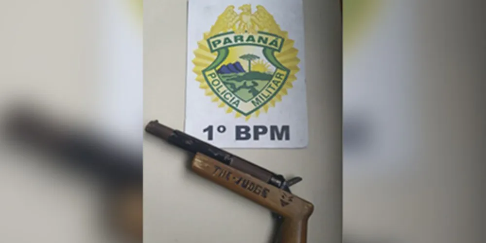 A arma de fogo, de calibre 12, é de fabricação caseira.  Ela possui a inscrição “The Judge”, possível menção ao filme “O Juiz”