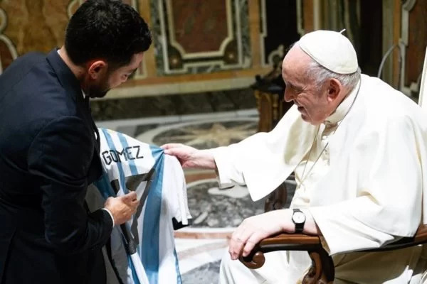 Papa segura o uniforme e olha atentamente para o objeto