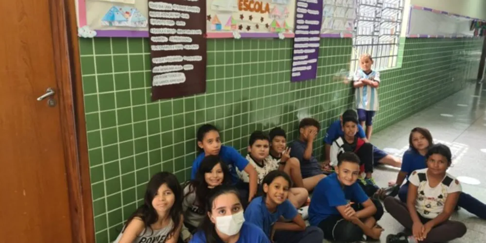 Os estudantes posando em frente aos cartazes por eles confeccionados