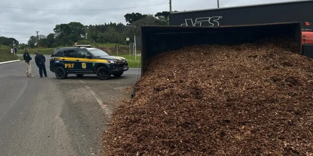 Um caminhão com placas de Prudentópolis, carregado com cavacos de madeira, tombou ao fazer a rotatória na BR-153