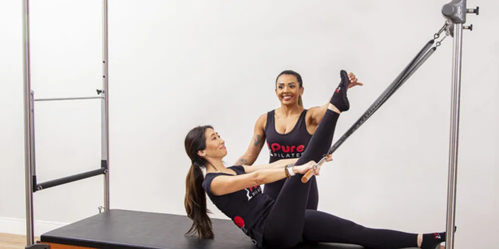 Professora de pilates auxilia aluna com execução correta