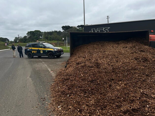 Um caminhão com placas de Prudentópolis, carregado com cavacos de madeira, tombou ao fazer a rotatória na BR-153