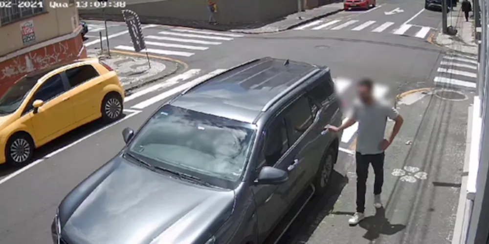 Nas imagens, é possível ver o suspeito olhando para os lados, mexendo na maçaneta do carro, até que entra no veículo e, após um tempo, sai com a bolsa.