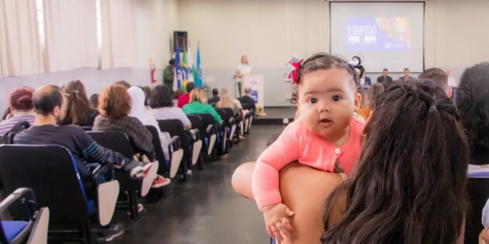 A estudante Hemili Maruim assiste a uma palestra na UEPG  e no seu colo está sua filha, a pequena Melanie.