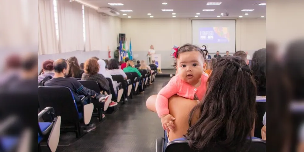 A estudante Hemili Maruim assiste a uma palestra na UEPG  e no seu colo está sua filha, a pequena Melanie.