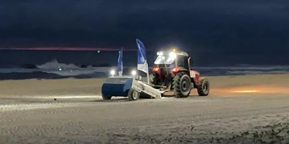 Máquina saneadora inicia limpeza da areia da praia