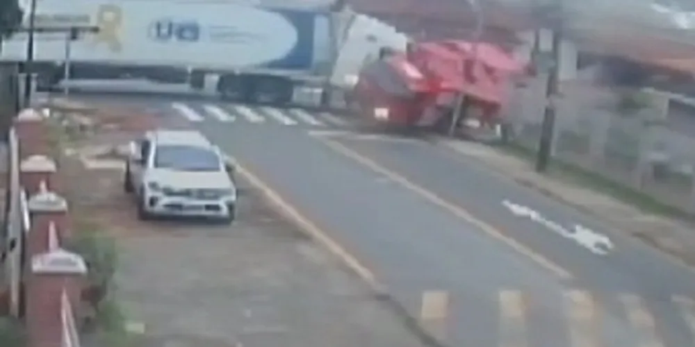 Com o impacto da batida, o caminhão vermelho acaba tombando