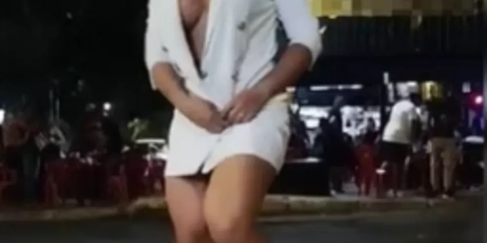 Com outra pessoa gravando com um celular, a mulher sorria e dançava até abrir o blazer, que escondia a nudez completa