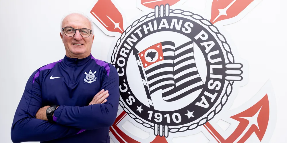 Dorival Júnior ao lado do escudo do Corinthians