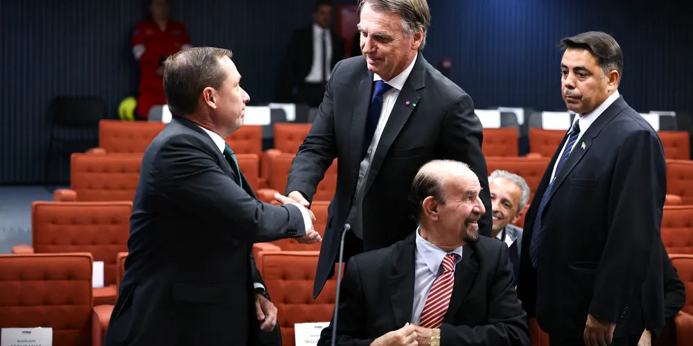 Mauro Cid cumprimentando Jair Bolsonaro, durante depoimento dos réus