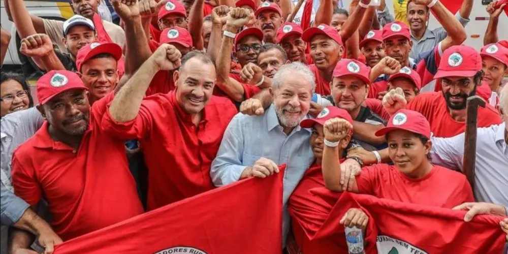 Lula segundando uma bandeira do MST