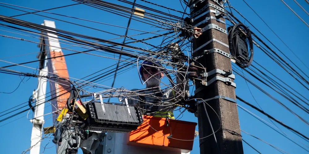 Funcionários da Copel fazem a retirada de fios sem utilidade dos postes no bairro Santa Paula.