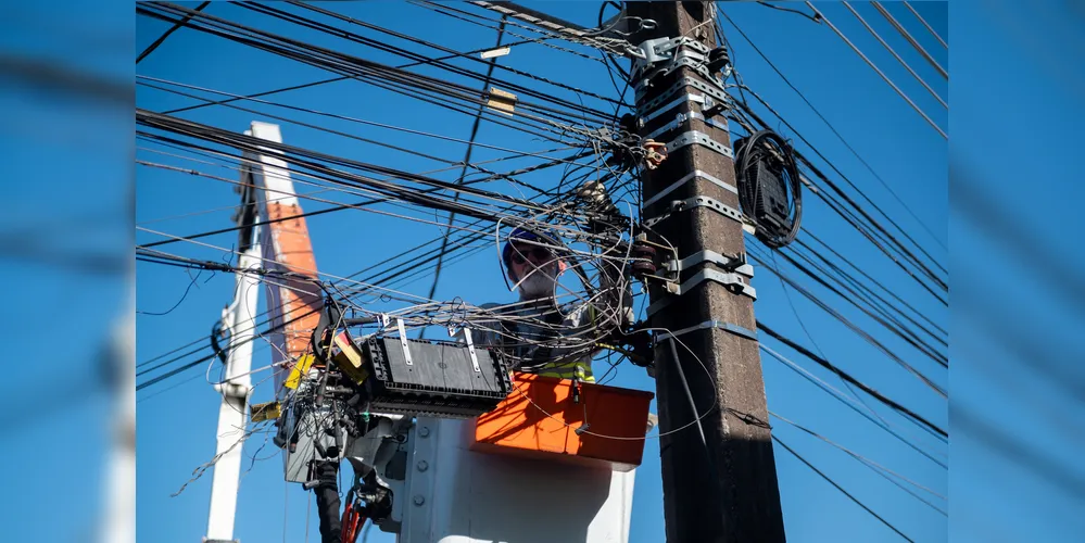 Funcionários da Copel fazem a retirada de fios sem utilidade dos postes no bairro Santa Paula.