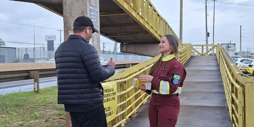 Socorrista da equipe de APH da PRVias orienta pedestre sobre importância de usar a passarela ao atravessar a rodovia na PR-445 em Londrina