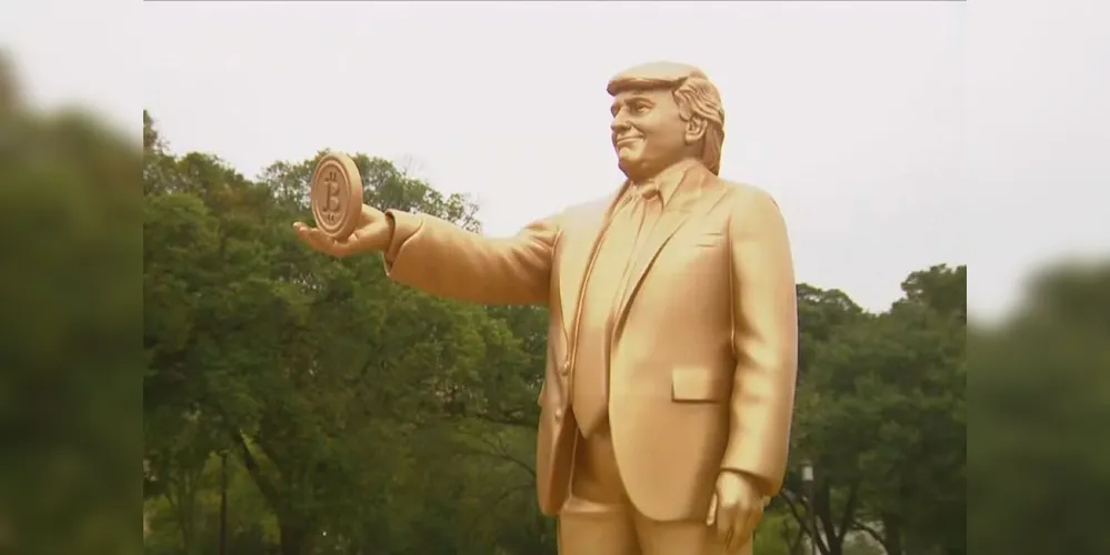 Estátua dourada de Donald Trump segurando um Bitcoin