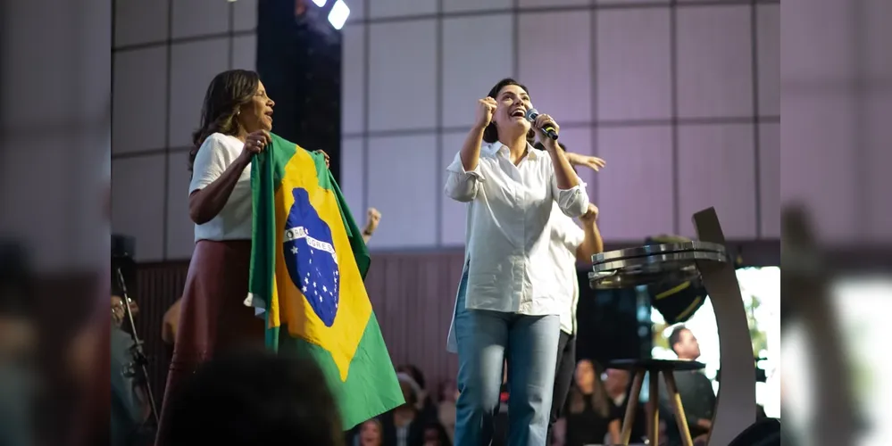 Michelle Bolsonaro ao lado da bandeira do Brasil