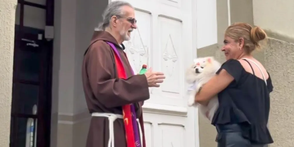 Frei capuchinho abençoando um cachorro no colo de uma mulher