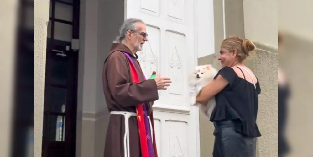 Frei capuchinho abençoando um cachorro no colo de uma mulher
