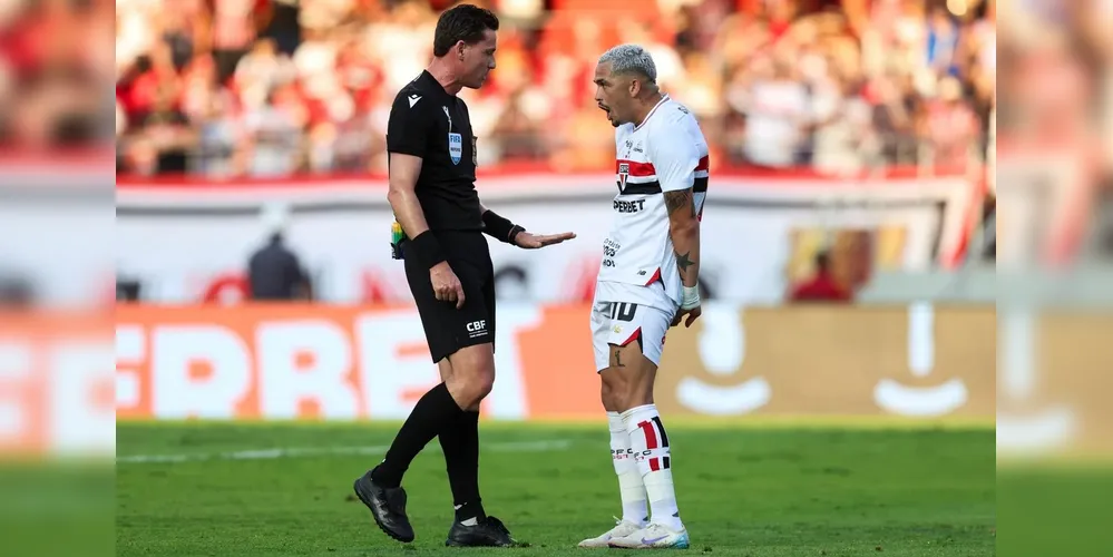 Árbitro e jogador do São Paulo durante partida