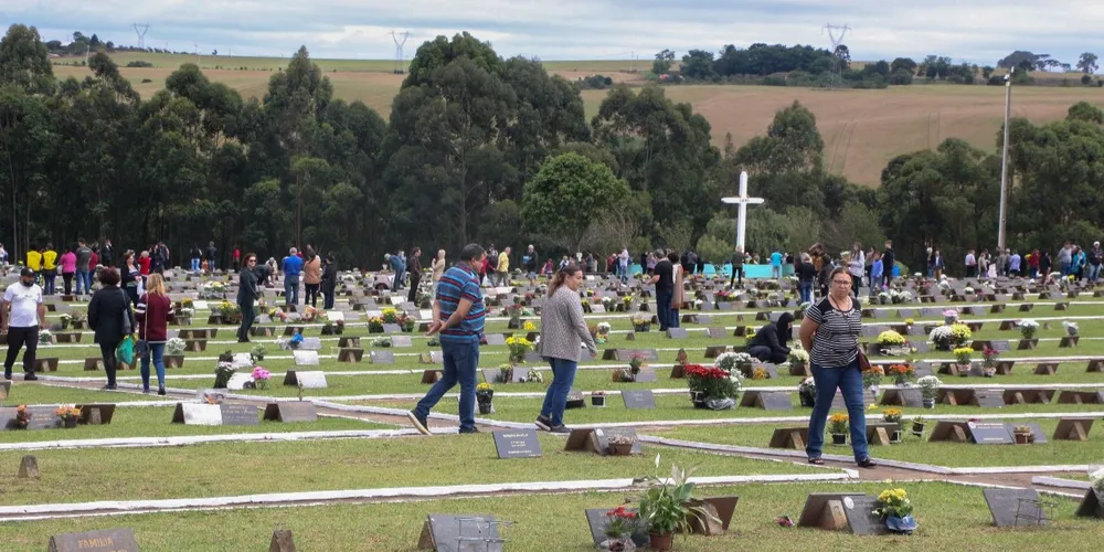 Pessoas visitando seus entes queridos em túmulos