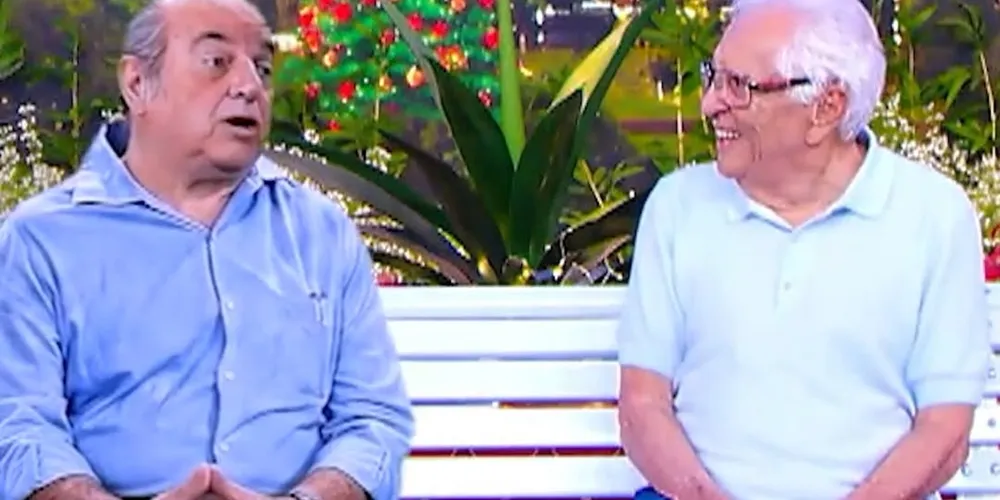 Manoel de Nóbrega em IA e seu filho, Carlos Alberto de Nóbrega, sentados no banco da 'A Praça é Nossa'