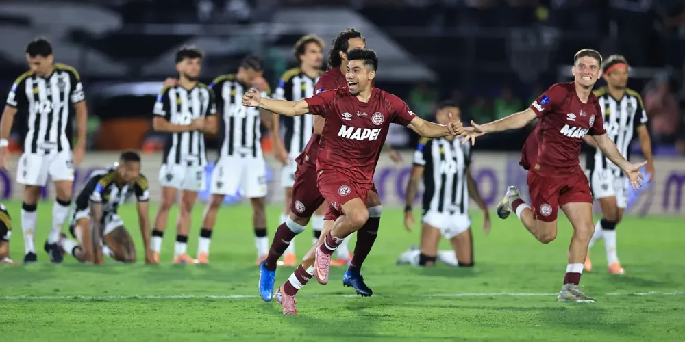 Jogadores do Lanús comemoram a vitória nos pênaltis na final na Sul-Americana, enquanto os atleticanos lamentam ao fundo