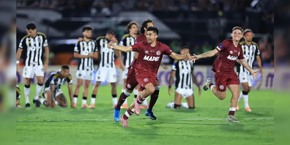 Jogadores do Lanús comemoram a vitória nos pênaltis na final na Sul-Americana, enquanto os atleticanos lamentam ao fundo